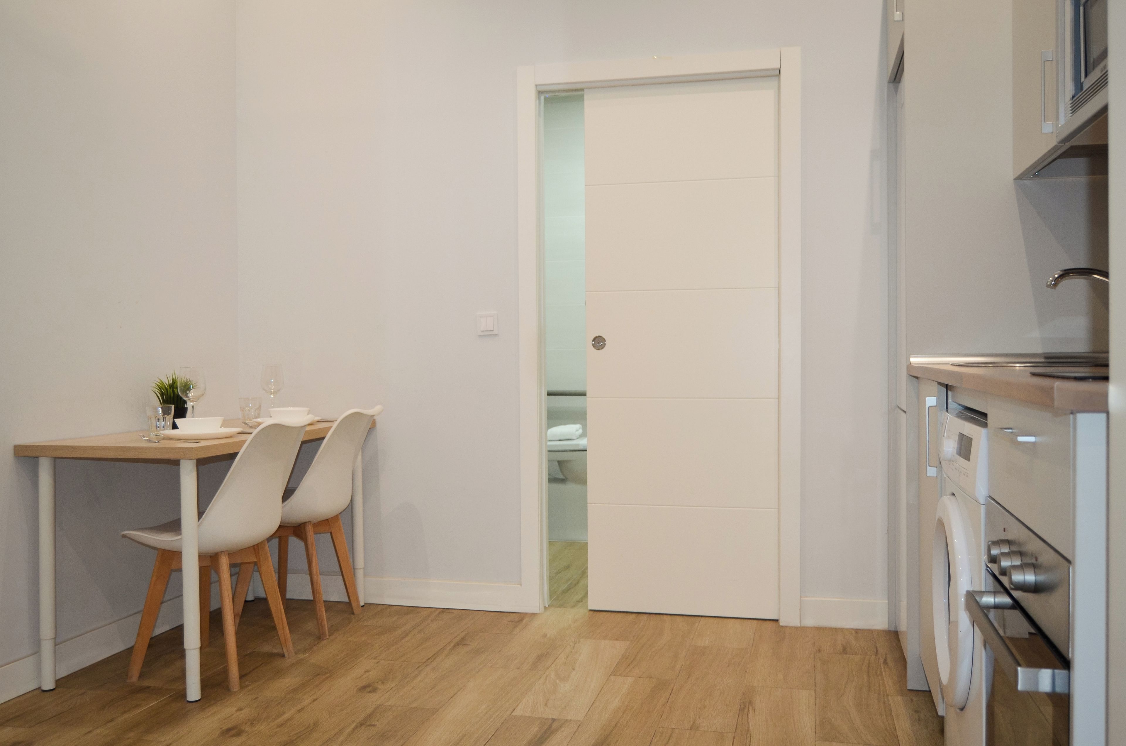 Una cocina compacta con comedor, lavadora y puerta que da a un baño.