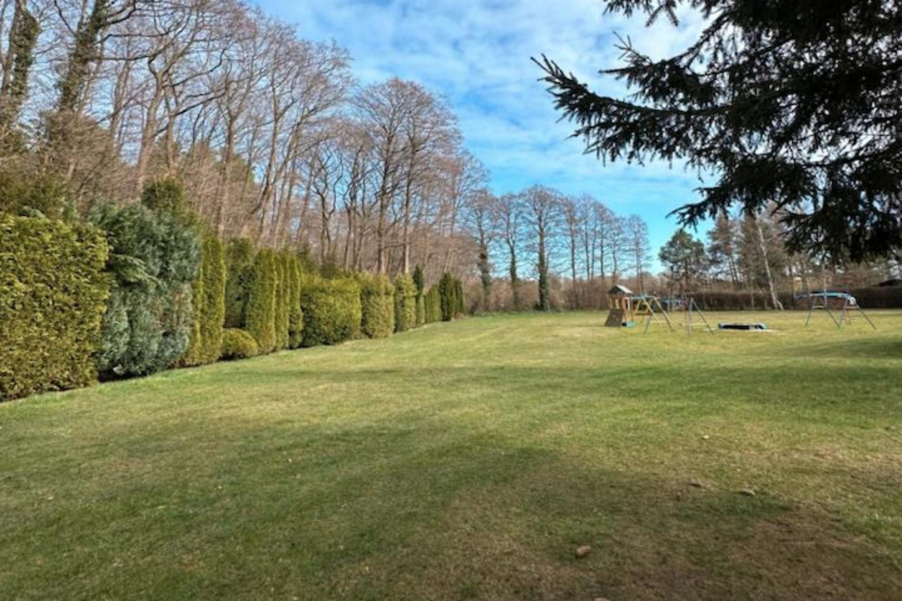 A grassy yard with a wooden play structure and a small shed.