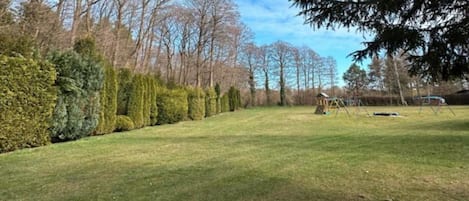 A grassy yard with a wooden play structure and a small shed.