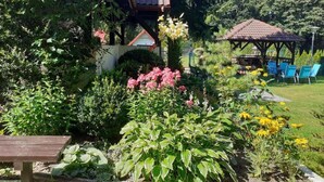 A garden with a gazebo, a bench, and a variety of plants. - Large and Comfortable Holiday Villa With a Garden (Choczewo)