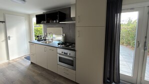A modern kitchen with a built-in oven, a sink, and a gas stove. - Chalet 56 in Stegeren Near the Heathlands (Stegeren)