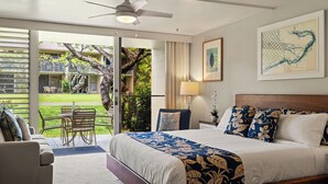 Un dormitorio con una cama, ventilador de techo, ventana y vistas a un jardín.