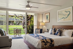 A bedroom with a bed, a ceiling fan, a window, and a view of a garden. - New Listing! Cozy studio for 4 in steps from the beach - Napili Shores C120 (Lahaina)