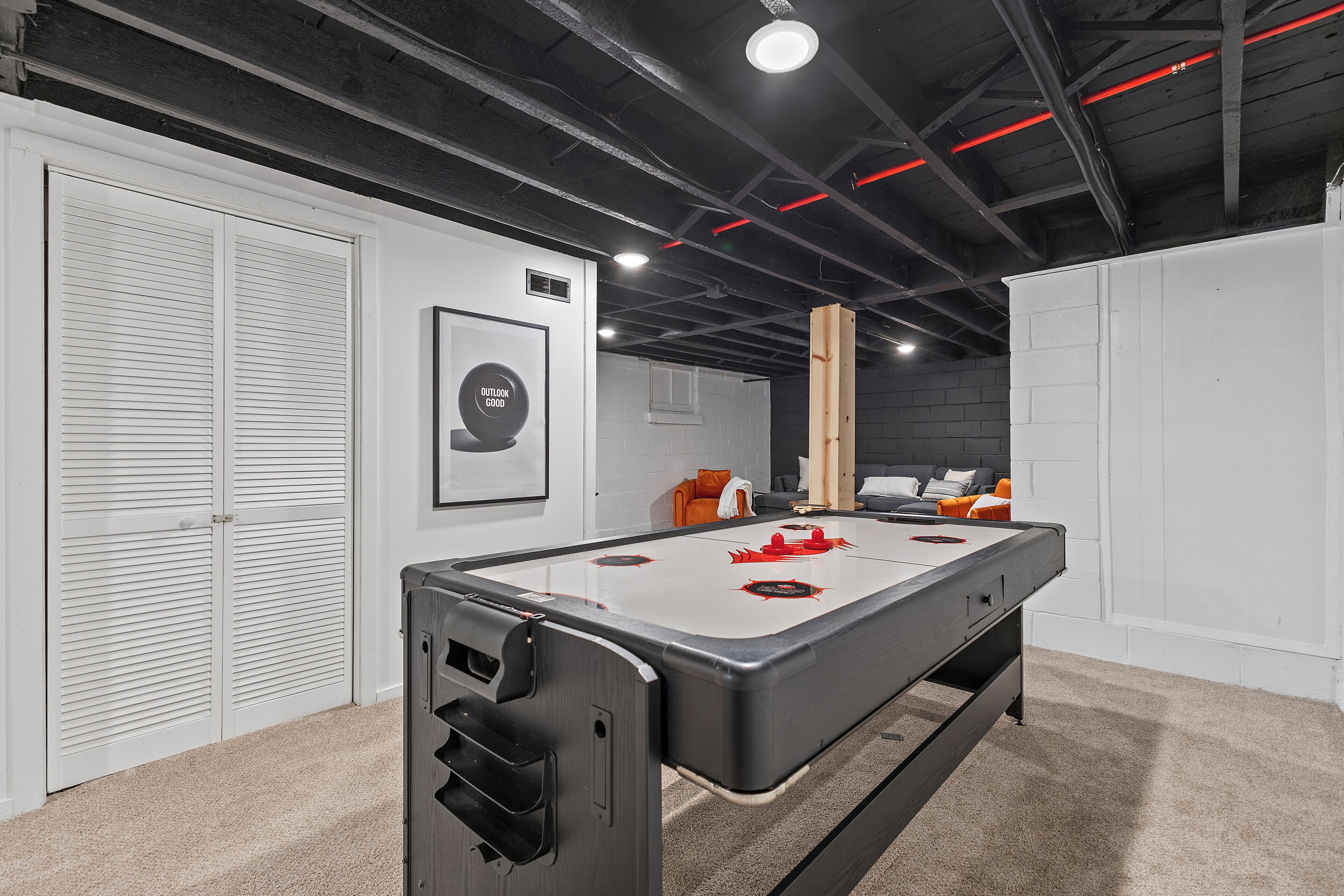 A pool table in a room with white walls, a ceiling with exposed beams, and a door with louvered panels.