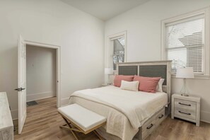 A bedroom with a bed, bedside tables, a bench, and a door. - *NEW* Cozy Chic 1BR Downtown Chattanooga (Chattanooga)