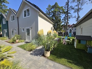 A residential building with a well-maintained garden, outdoor seating area, and a children's play structure. - Large Holiday Homes With Beautiful Gardens (Rewal)