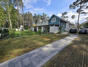 Ein Wohngebiet mit gepflastertem Weg, einer kleinen Rasenfläche und einer Reihe von Häusern mit Garage.