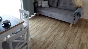 Una stanza con un divano grigio, un tavolo da pranzo in legno e sedie bianche.