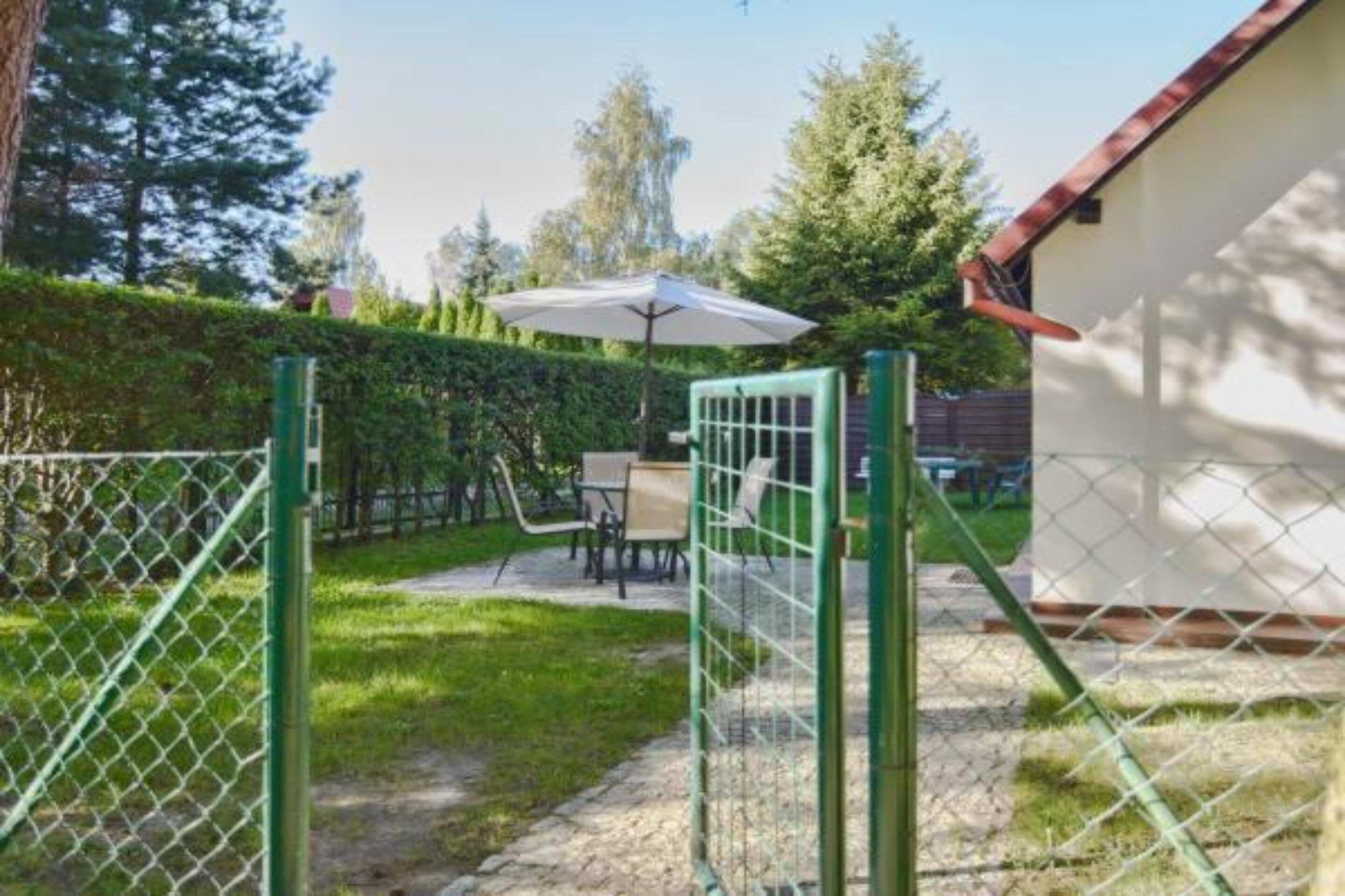 A gated backyard with a patio area, a table, and an umbrella.