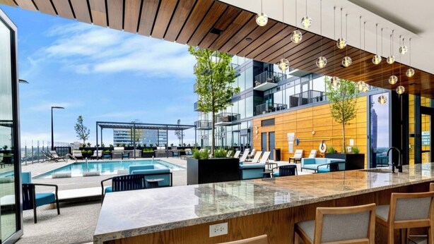 A modern bar area with a pool, outdoor seating, and a view of the cityscape.