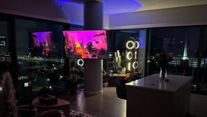 A modern living room with a large TV, a coffee table, and a view of a cityscape.