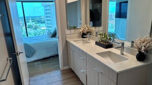A modern bathroom with a large mirror, two sinks, and a view of the city through a large window.