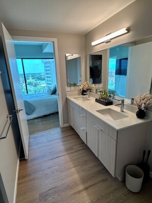 A modern bathroom with a large mirror, two sinks, and a view of the city through a large window. - Luxury Raleigh Condo w/ Panoramic City Sunset Views (Raleigh)
