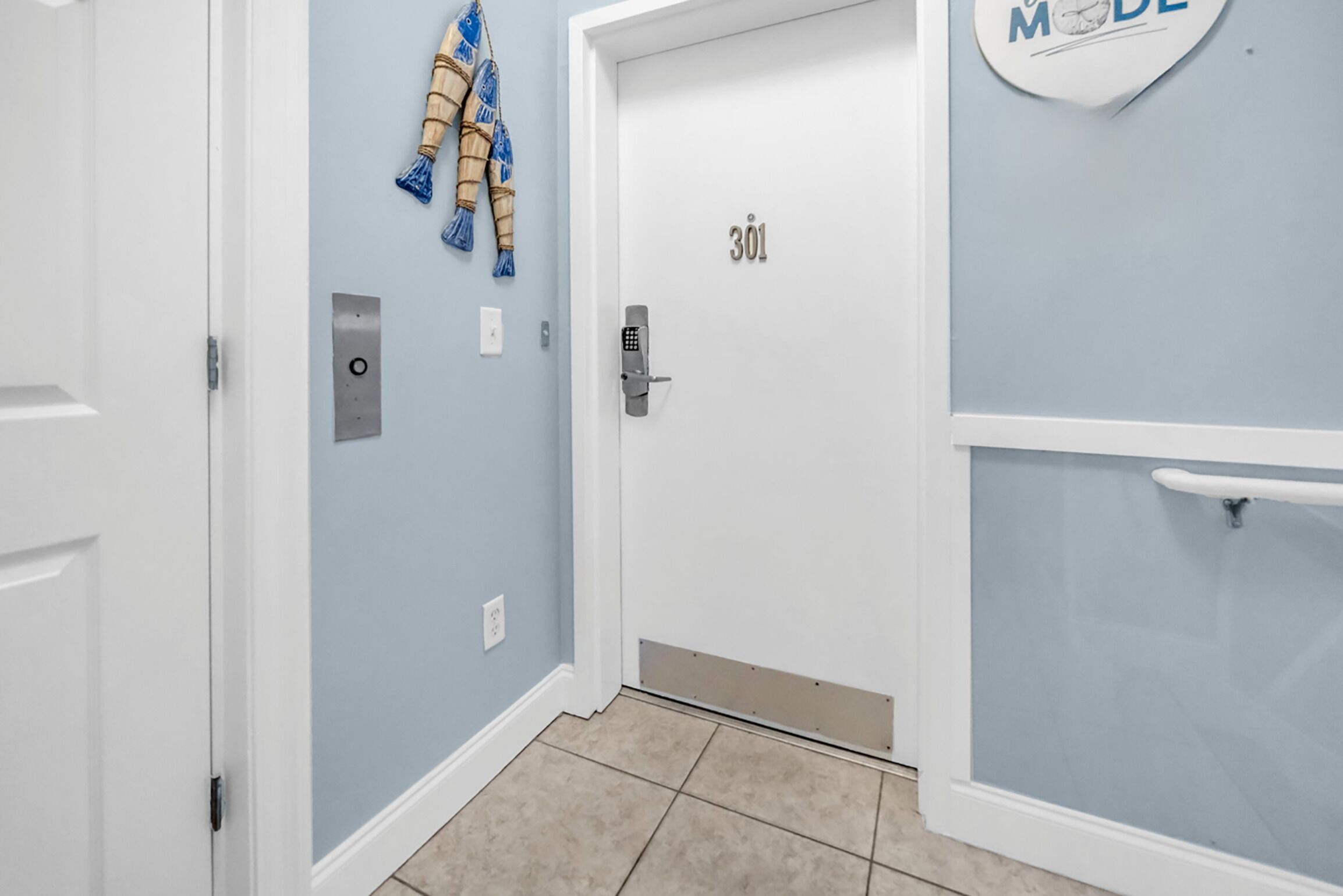 Un couloir avec une porte portant le numéro « 301 », une serviette accrochée au mur et un panneau indiquant « MODE ».
