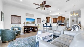 A spacious living room with a ceiling fan, a kitchen area, and a dining area. - Vista del Mar II - Coastal Calm PCB 301 (Panama City Beach)