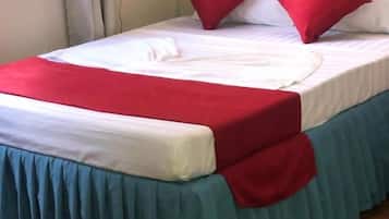 A bed with a white mattress, red and blue bed skirt, and two red pillows.
