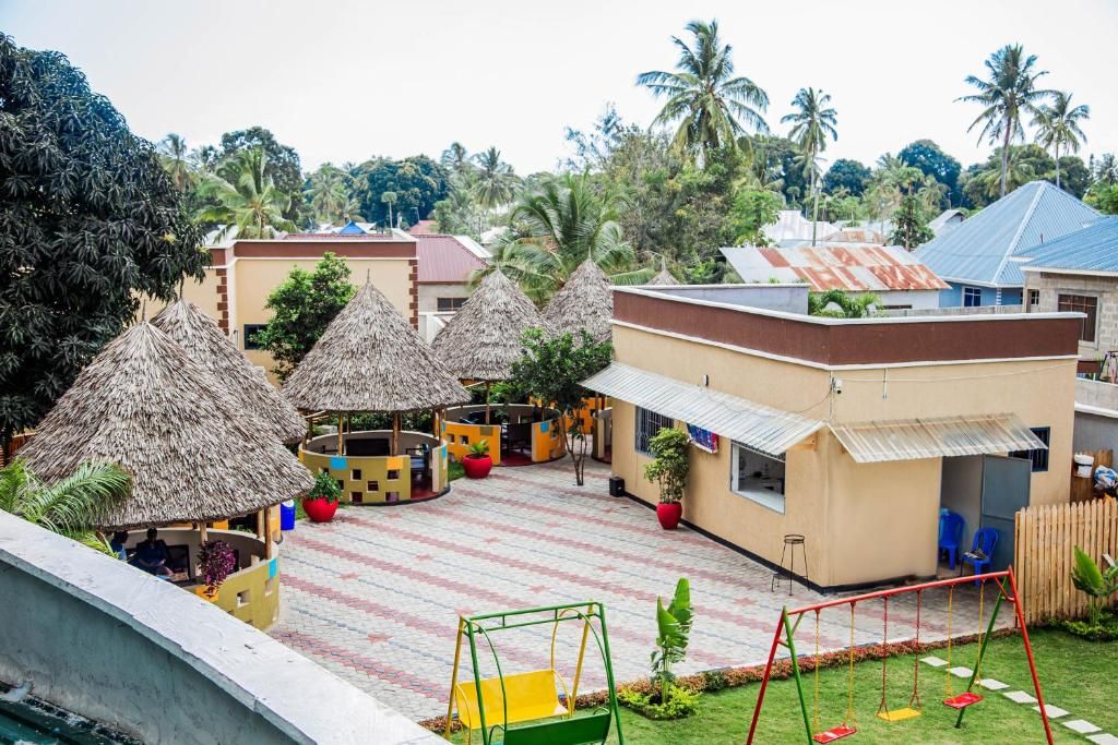 A courtyard with thatched-roof structures, a play area, and a building with a corrugated metal roof.