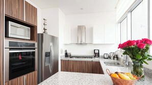 Een moderne keuken met inbouwapparatuur, een granieten aanrecht en een bloemenvaas.