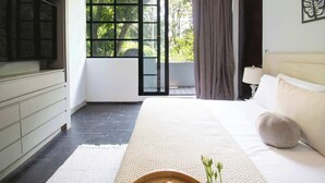 A modern bedroom with a large bed, a TV, a window with curtains, and a view of greenery outside. - 6BR house in Amsterdam street | Parque México (Mexico City)