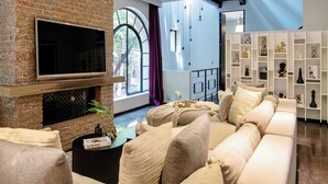 A living room with a brick fireplace, a large TV, a sofa, and a bookshelf with decorative items. - 6BR house in Amsterdam street | Parque México (Mexico City)