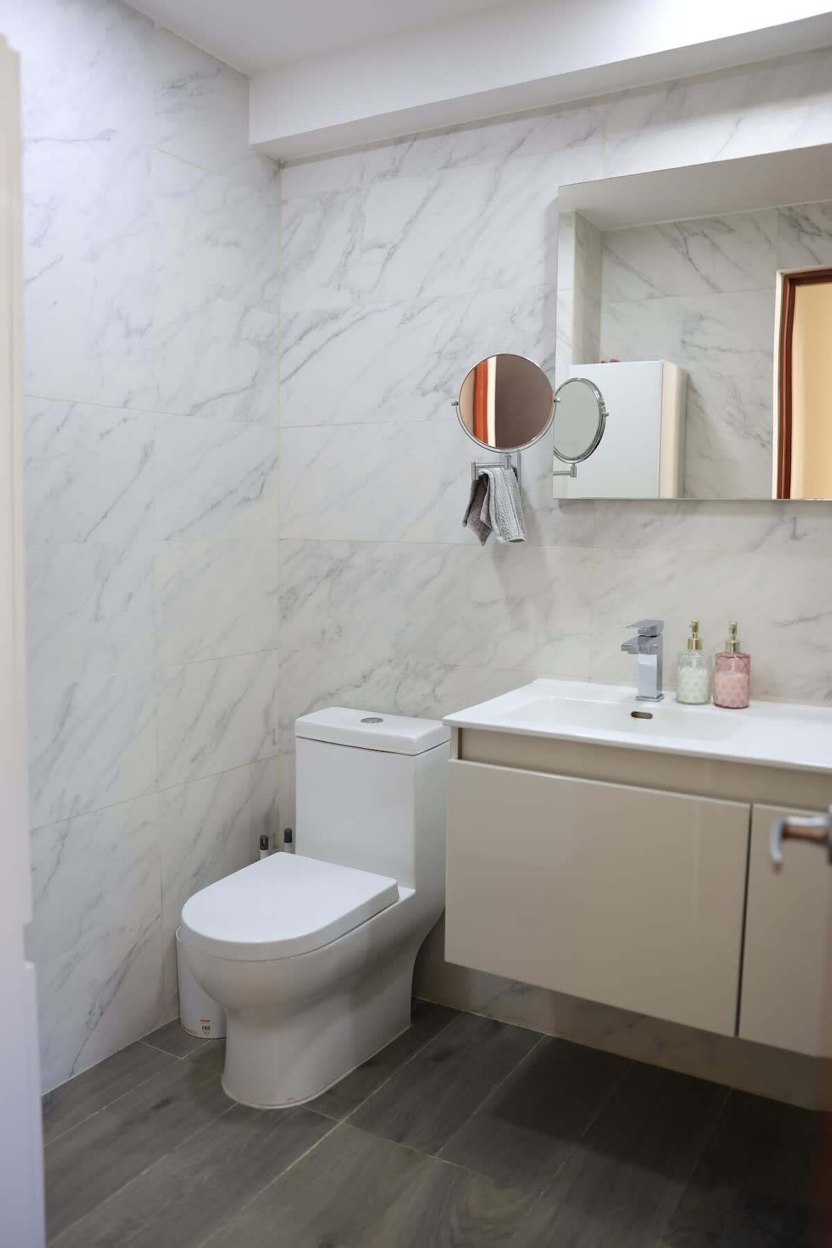 Un baño con inodoro, lavabo, espejo y toallero.