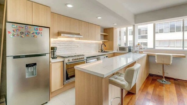 Una cocina moderna con una isla central, horno empotrado y refrigerador.
