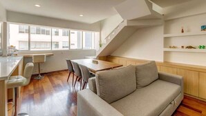 Un interior moderno con zona de comedor, sofá y escalera.