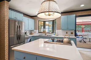 A kitchen with a central island, stainless steel refrigerator, and light blue cabinets. - Cedar Hall - A Charming Vintage Estate (Lebanon)