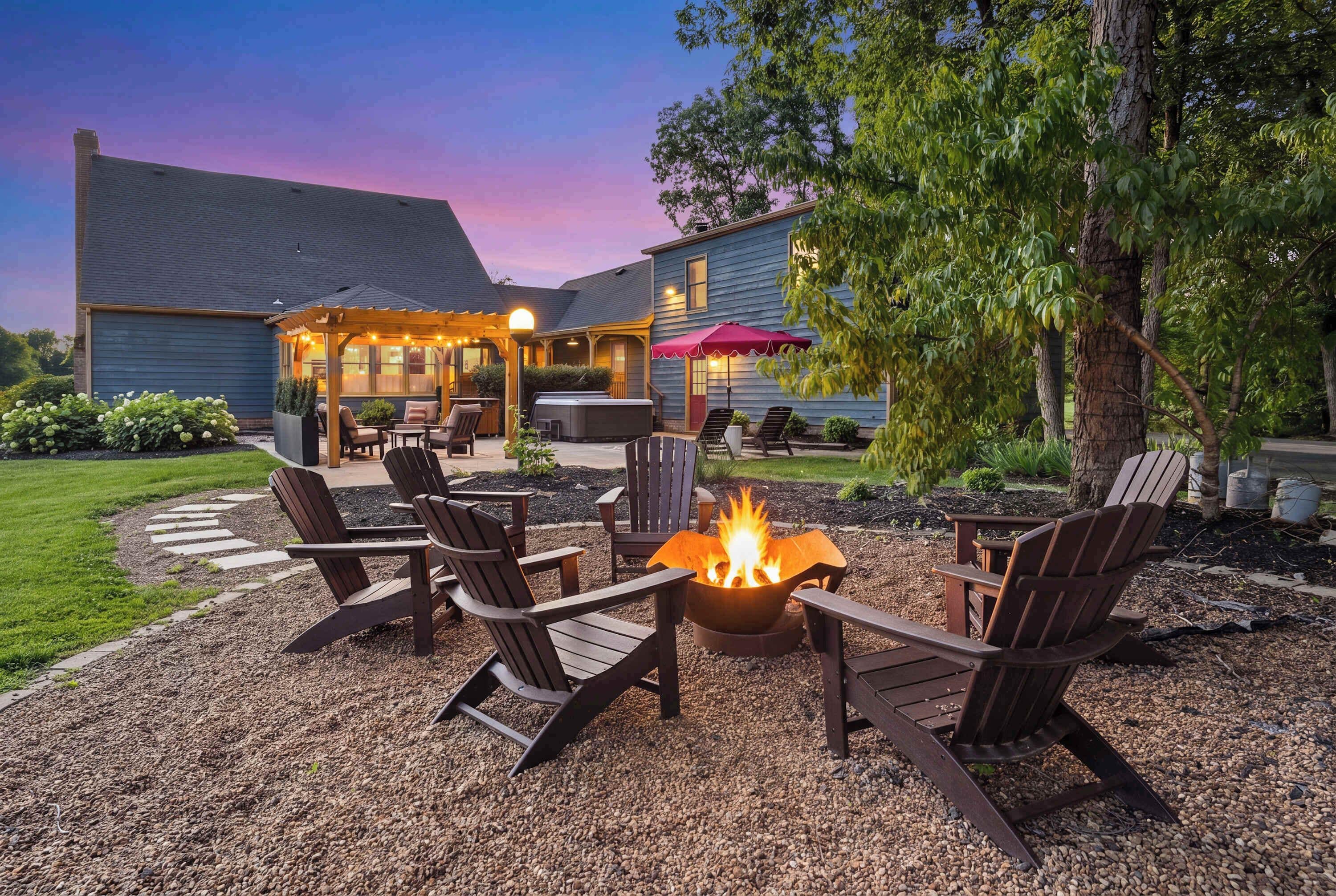 A patio with Adirondack chairs, a fire pit, and a covered seating area with a red umbrella.