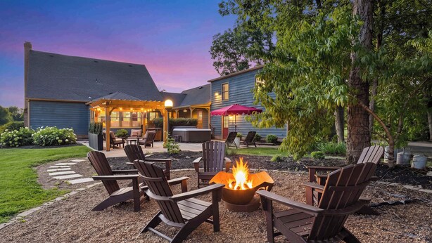 A patio with Adirondack chairs, a fire pit, and a covered seating area with a red umbrella. - Cedar Hall - A Charming Vintage Estate (Lebanon)