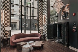 A modern interior with a large window, a checkered wall pattern, a fireplace, and a sofa. - Starr Piano - Roxie and Carraway Suites  - 8 Bedrooms (Nashville)