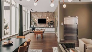 Una cocina moderna con pared de ladrillo, televisor de pantalla plana y ascensor.