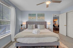 Ein Schlafzimmer mit einem Bett, zwei Nachttischen, einem Deckenventilator und Kunstwerken an der Wand.