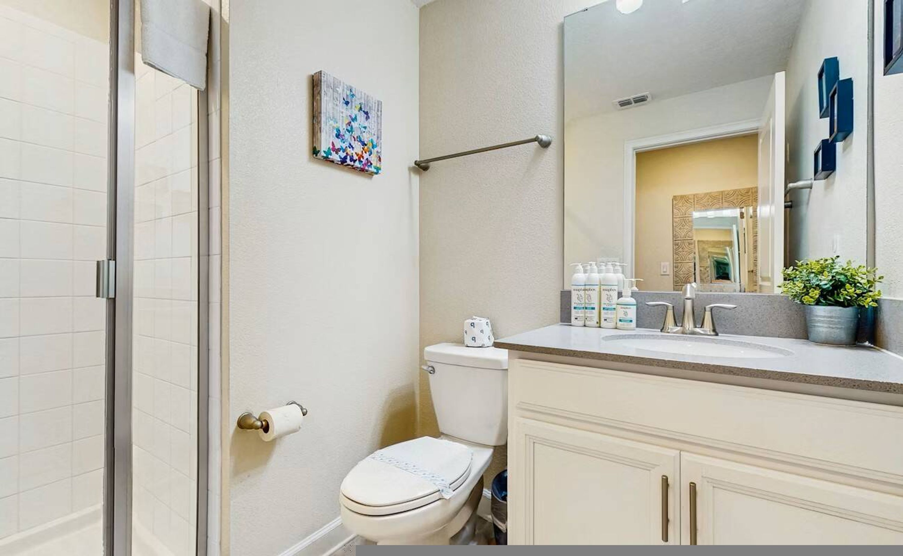 Une salle de bain comprenant des toilettes, un lavabo, un miroir et un espace douche.