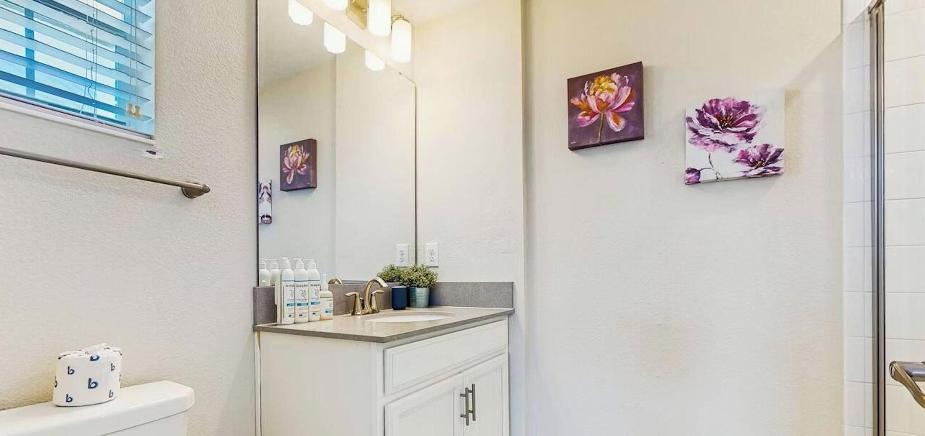 Baño con inodoro, lavamanos, espejo e iluminación en la pared.