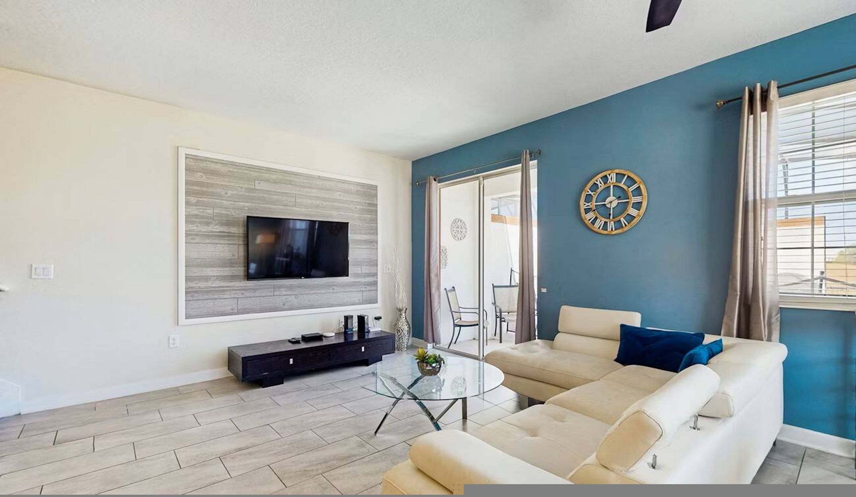 A living room with a TV, sofa, coffee table, and a clock on the wall.