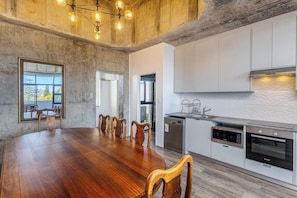 A modern kitchen with white cabinets, a built-in oven, and a dishwasher. - Urban Chic Retreat Stunning Mountain views by ctha (Cape Town)