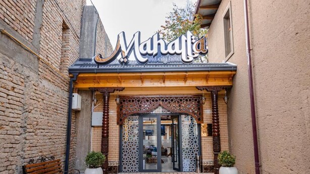 La entrada del hotel Mahala en la ciudad vieja, con fachada de madera, suelo con diseño y dos macetas.