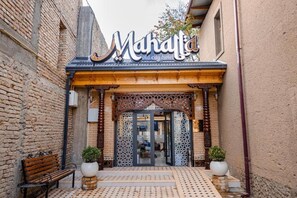 L’entrée de l’hôtel Mahala, situé dans la vieille ville, se distingue par sa façade en bois, son sol à motifs et les deux plantes en pot qui l’agrémentent.