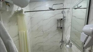 Baño con inodoro, lavabo, ducha y espejo.