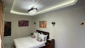 Un dormitorio con cama, mesitas de noche, candelabro, obras de arte en las paredes y alfombra estampada.