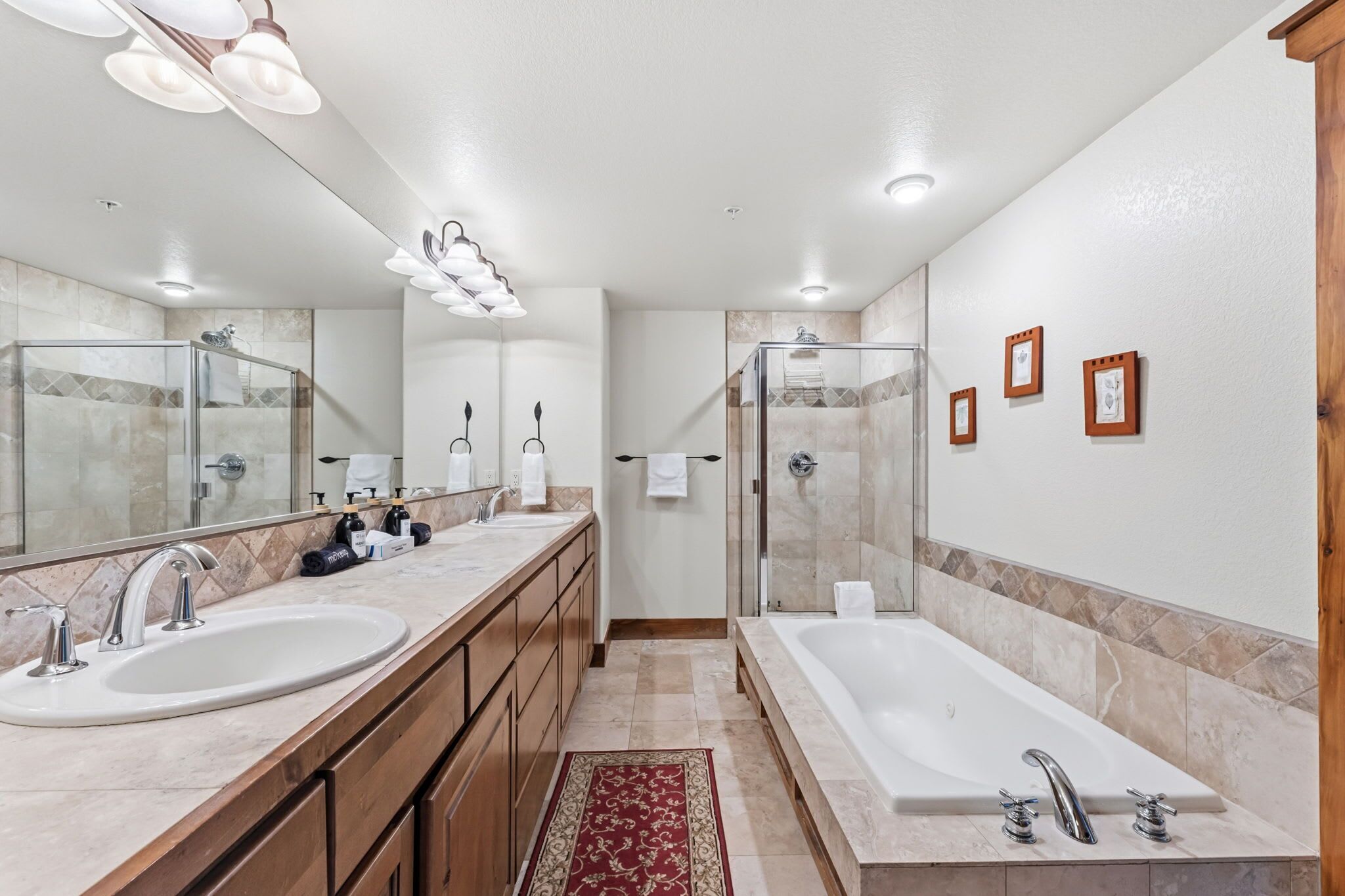 A modern bathroom with two sinks, a large bathtub, and a walk-in shower.