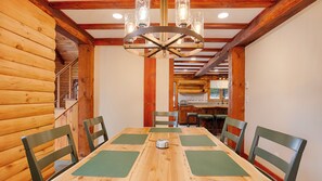 A wooden interior with a dining table, chairs, and a chandelier. - Cedar & Stone: Keuka Lake Retreat w/ Hot Tub & Golf (Hammondsport)