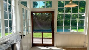A room with a wooden door, large windows, and a view of a swimming pool.