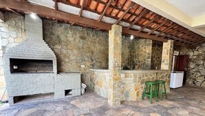 Cozinha com paredes de pedra, forno embutido, chão de pedra e teto de madeira.