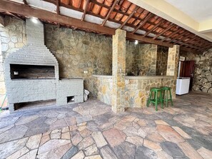 Cozinha com paredes de pedra, forno embutido, chão de pedra e teto de madeira.