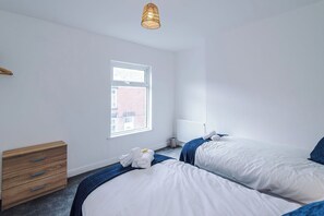 Ein Schlafzimmer mit zwei Betten, einer Holzkommode, einem Heizkörper und einem Fenster.