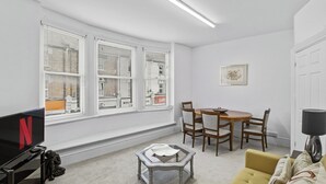 A living room with a TV, a dining table with chairs, a sofa, and a lamp. - Elegant 3BR | Short London Commute | Fast Wi-Fi (Greater London)