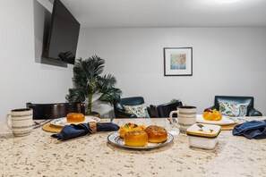 Ein Esstisch mit Speisen, Getränken, einer Pflanze und einem an der Wand befestigten Fernseher.