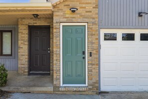 Une maison avec une porte marron, une porte verte et une porte de garage blanche.